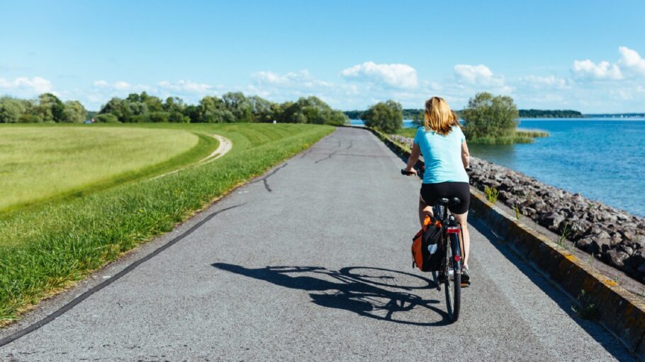 Cycliste pedalant sur une petite route goudronnee le long du lac du Der